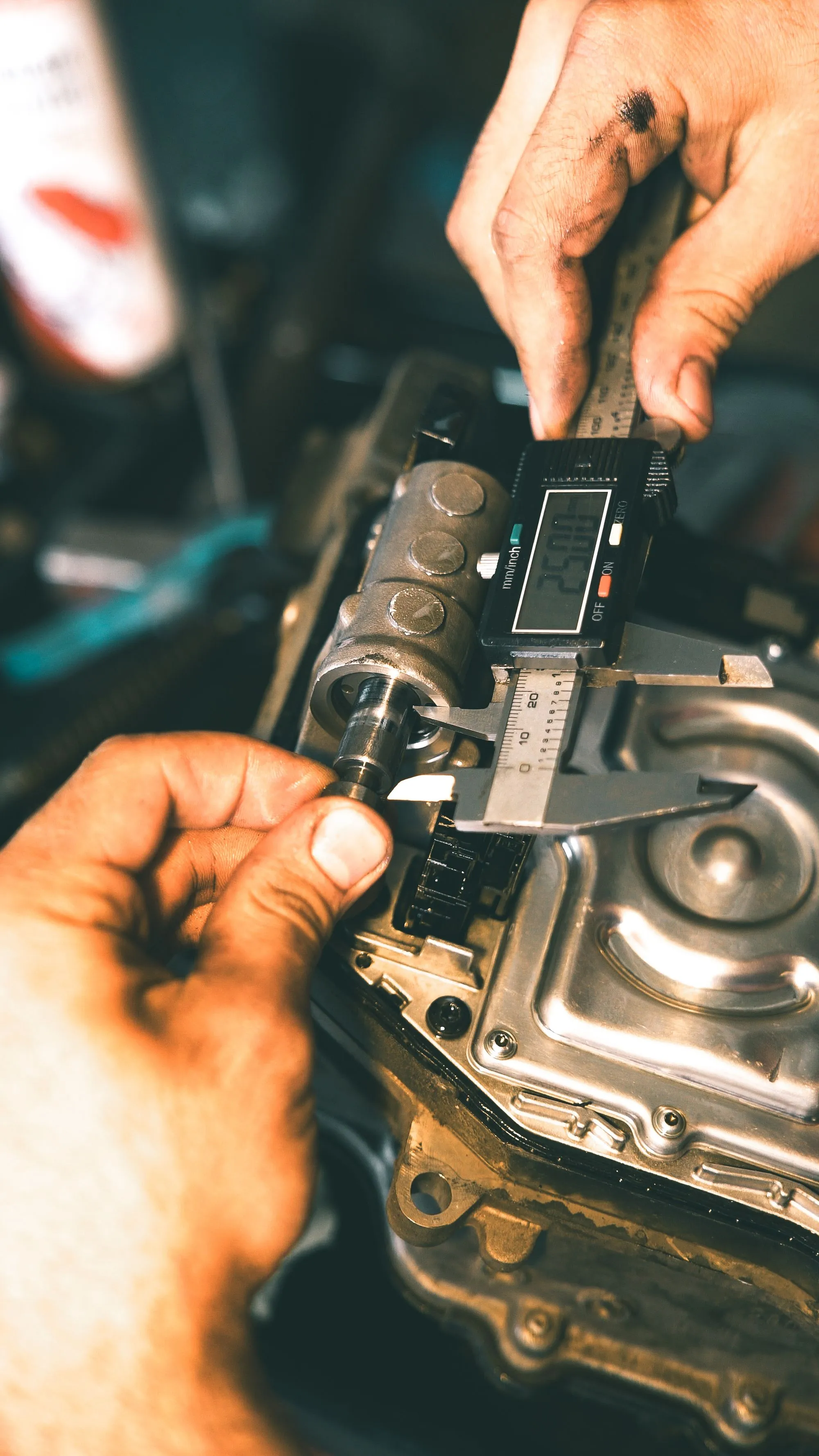 A machined metal component being checked with a digital caliper